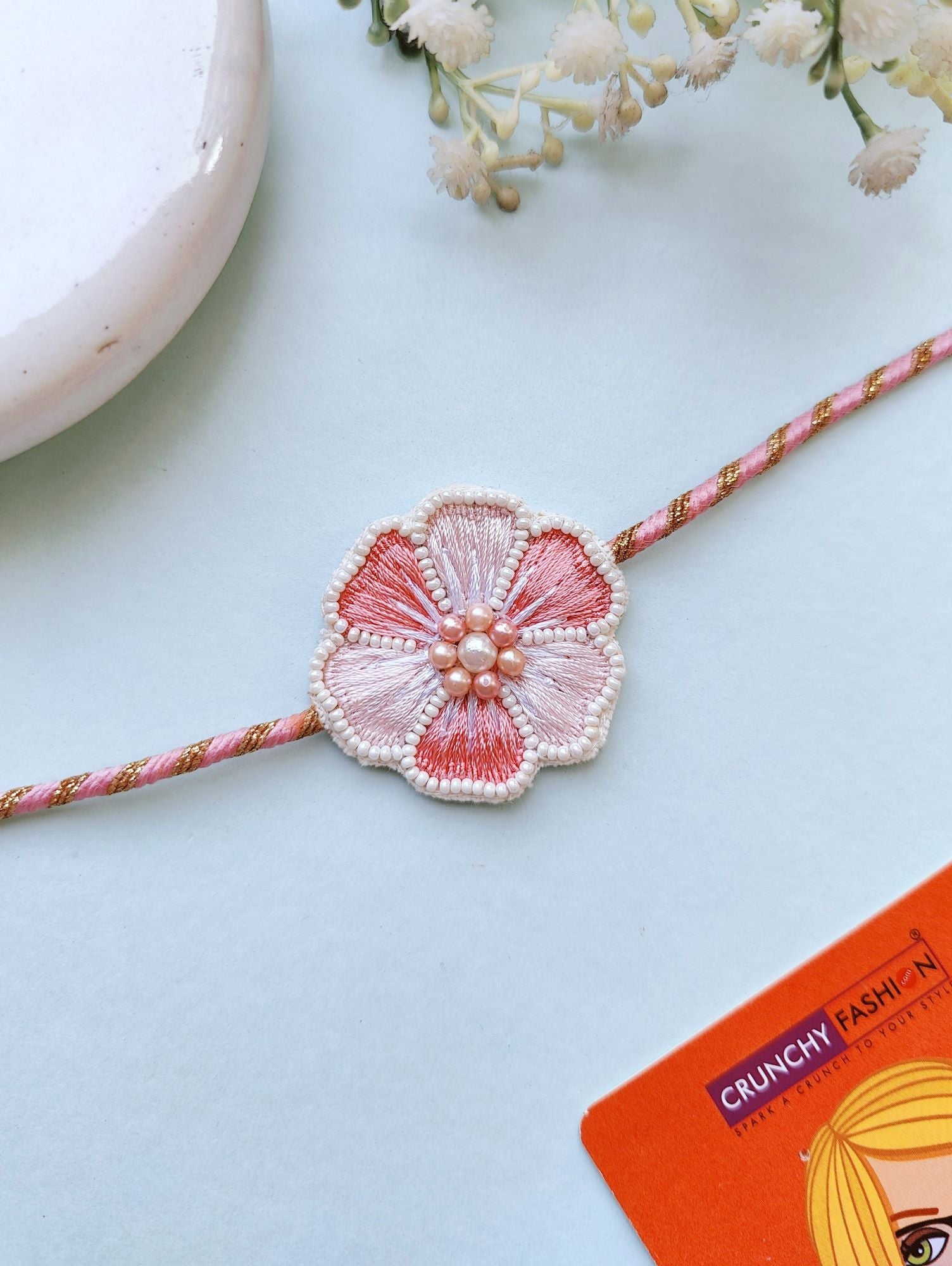 Handcrafted multi-color beaded Rakhi with pink flower design, adjustable for men and women