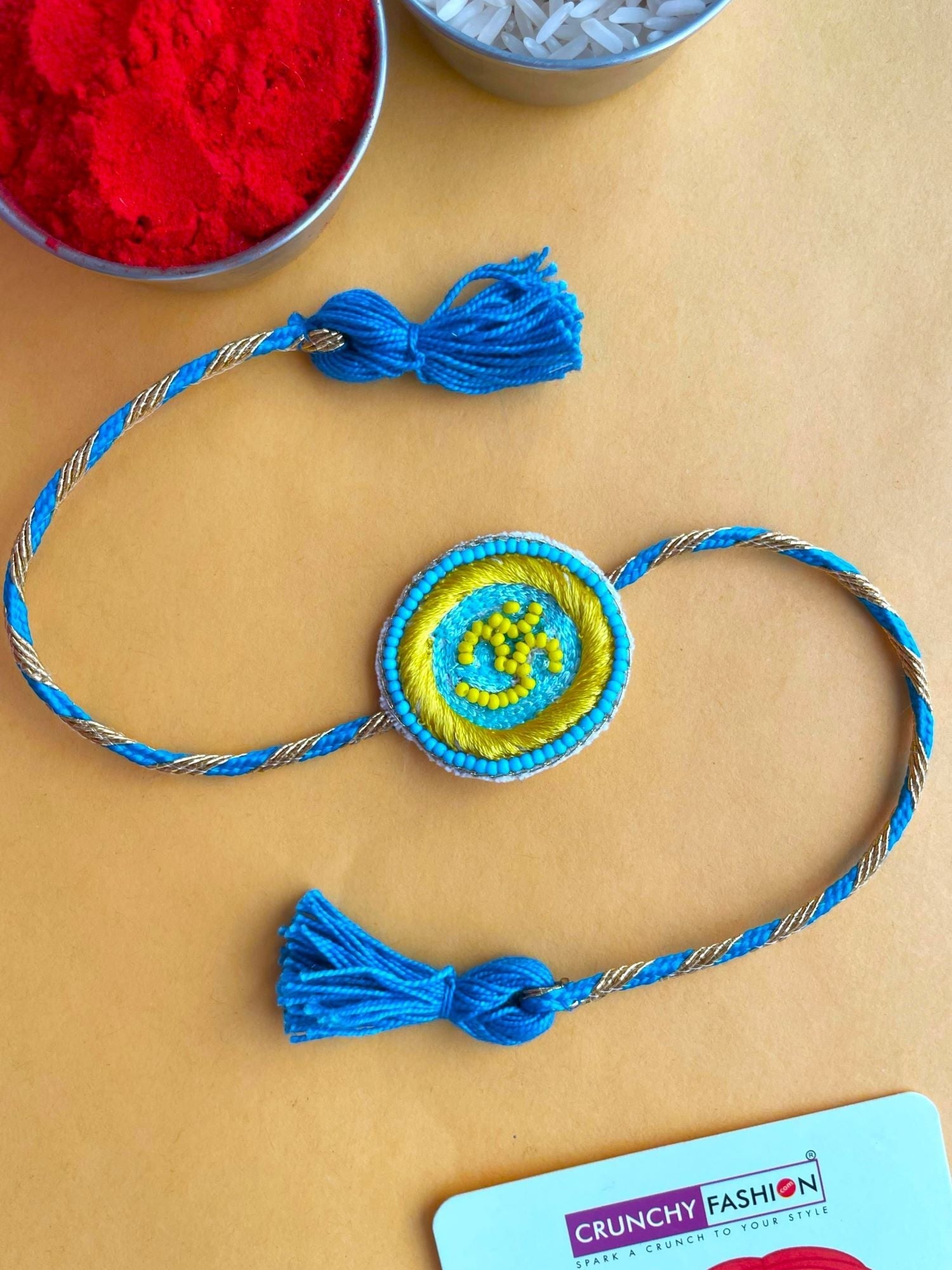 Sky-blue handmade OM Rakhi, ideal for brothers to celebrate Raksha Bandhan. Package includes beaded Rakhi, Roli and Chawal. Adjustable for a perfect fit.