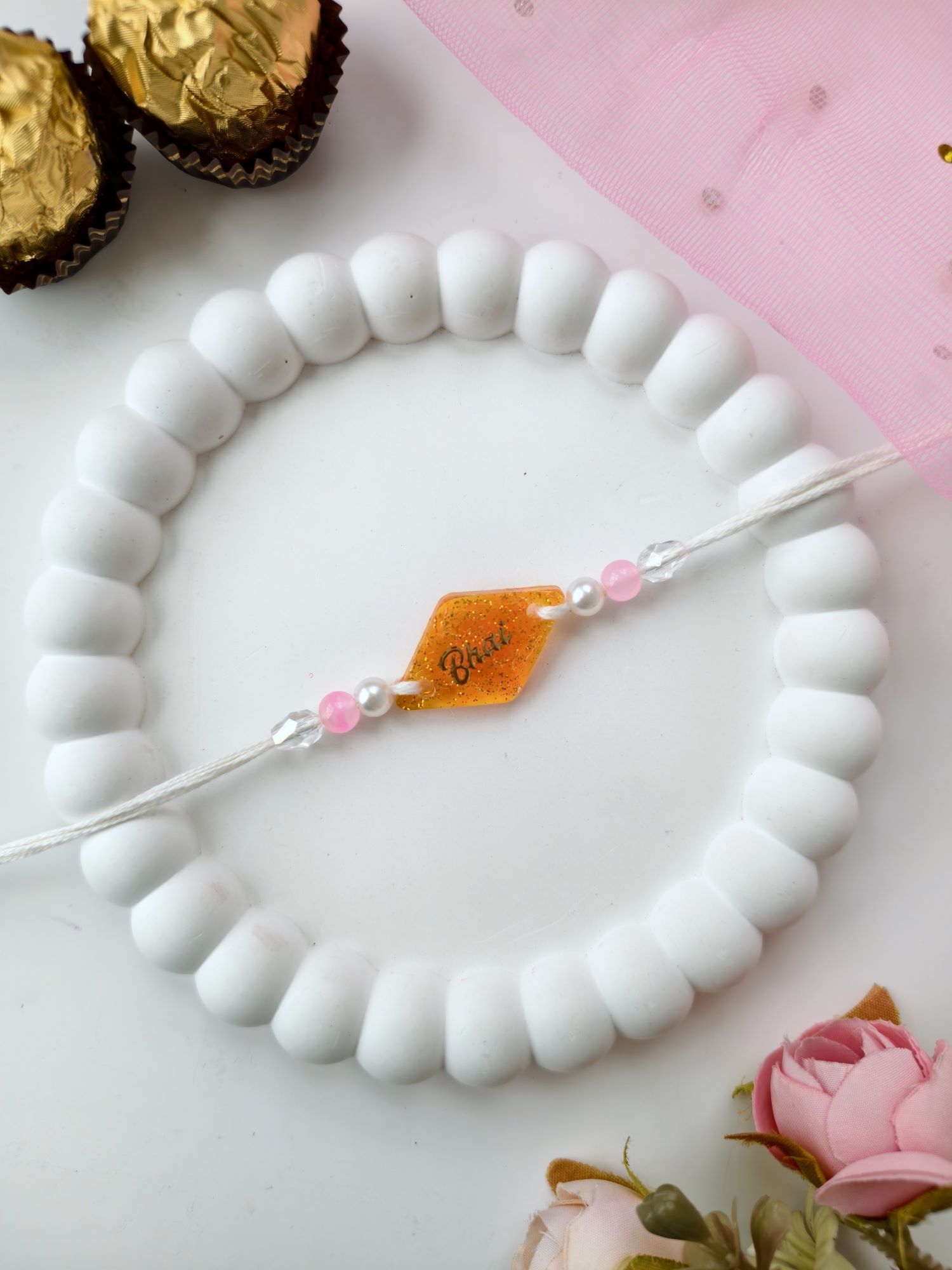 handmade orange resin rakhi 2026, sparkle bhai rakhi design