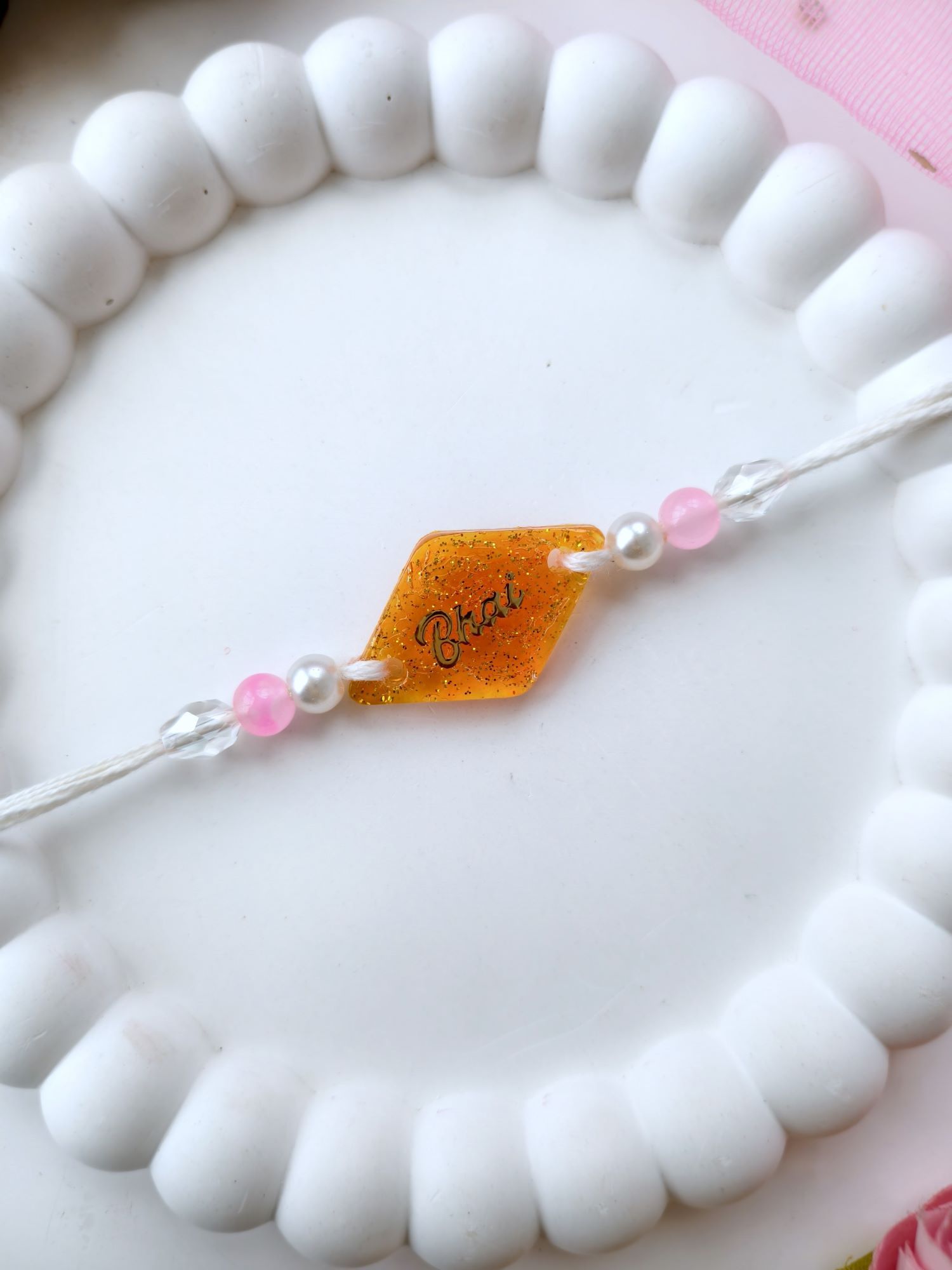 handmade orange resin rakhi 2026, sparkle bhai rakhi design