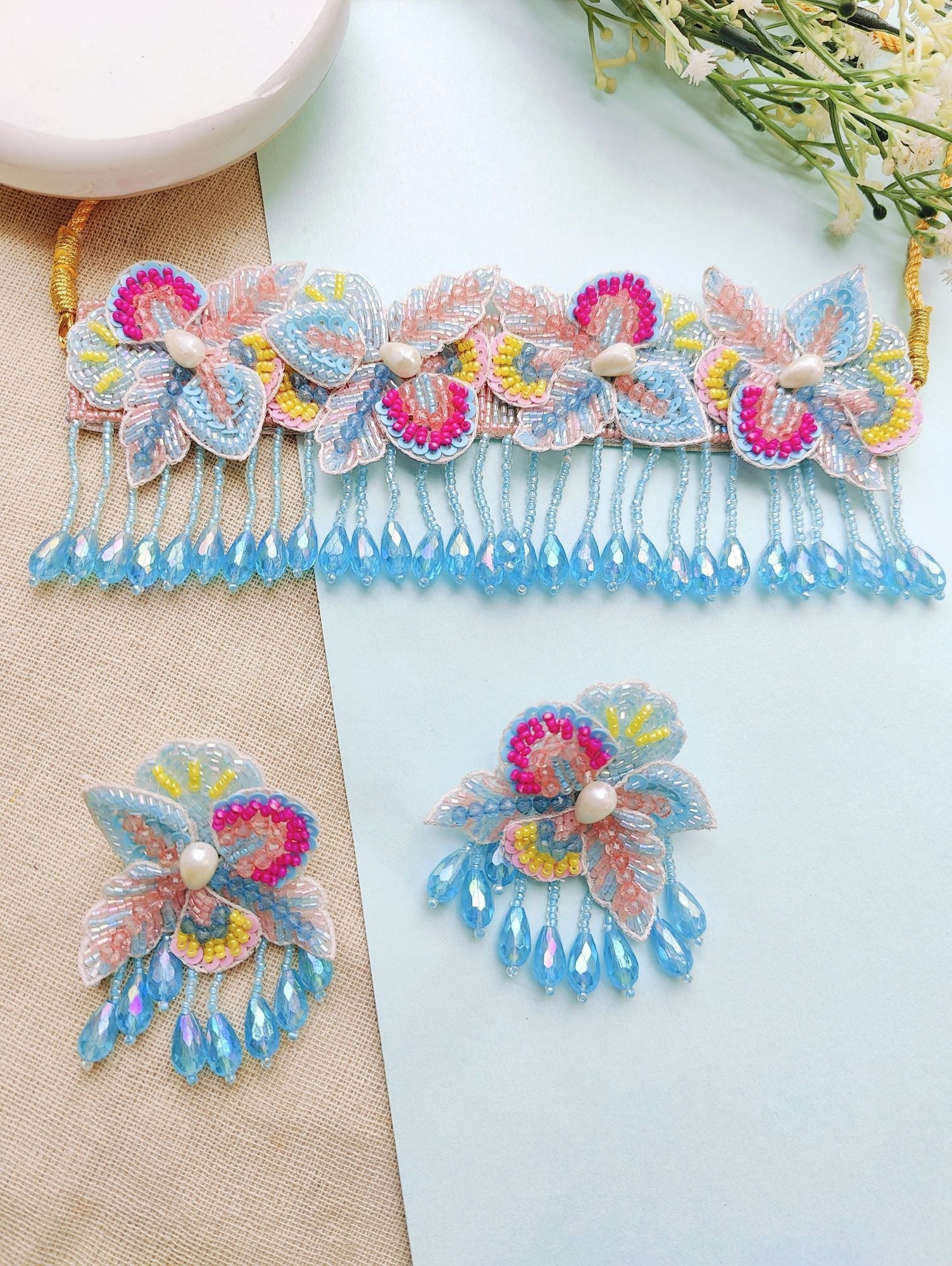 Elegant baby pink and sky blue floral haldi bridal jewellery set for women, featuring pearls and beads, ideal for weddings and festive occasions.