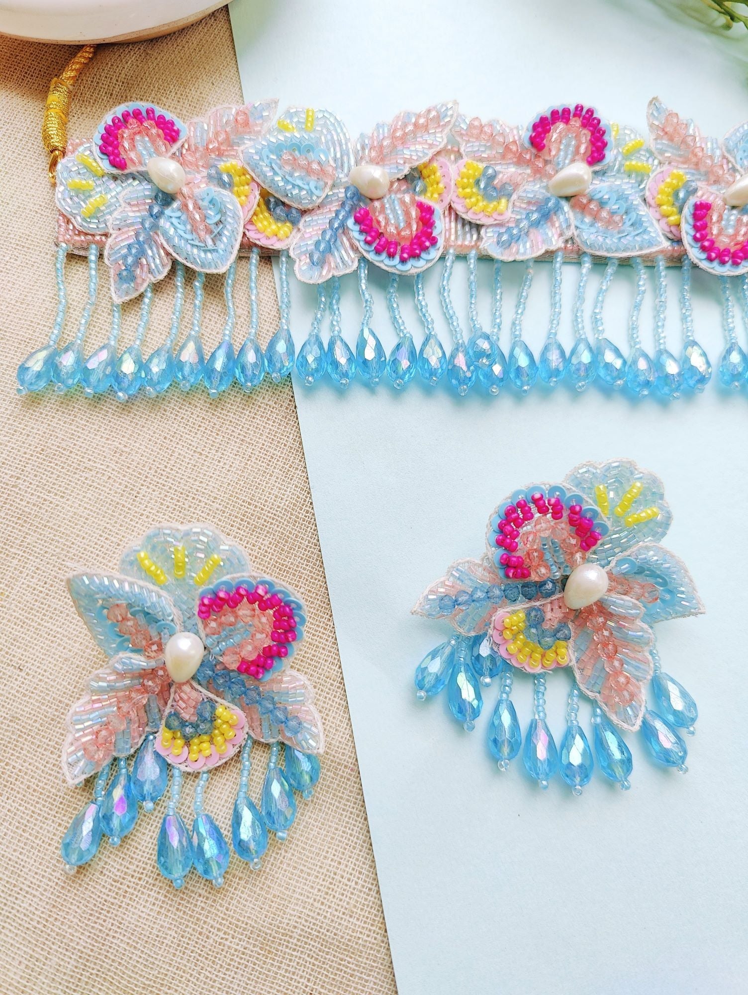 Elegant baby pink and sky blue floral haldi bridal jewellery set for women, featuring pearls and beads, ideal for weddings and festive occasions.