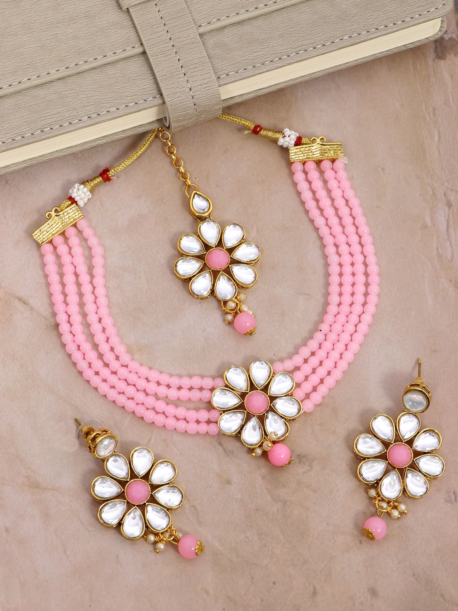 Gold plated bridal crystal choker necklace set with ball drops design and matching earrings and tika, ideal for various occasions like weddings, parties, in baby pink color.